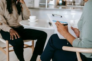 person sitting at table with clipboard, interviewing someone else at the table